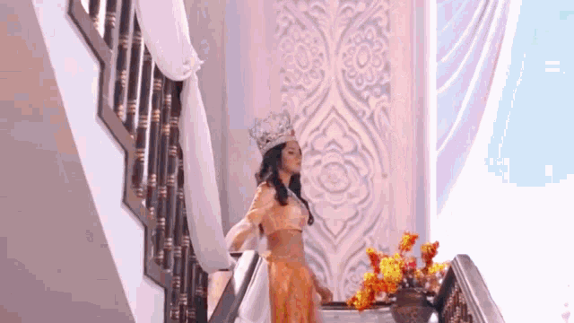 a woman in a crown is standing on the stairs .
