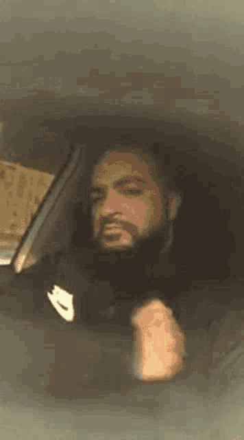 a man with a beard is driving a car and making a face .