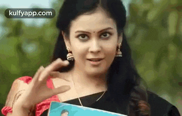 a woman in a saree is holding a picture of a man in a box .