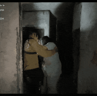 a man and a woman are hugging in a dark room with dh written on the bottom right