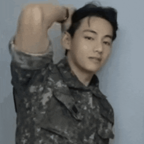 a young man in a military uniform is holding his hair .