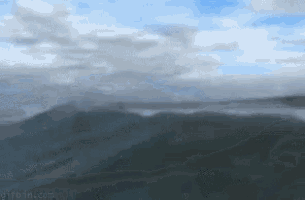 a painting of a mountain range with clouds in the sky .