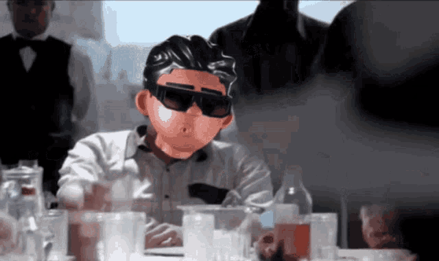 a man wearing sunglasses sits at a table with glasses