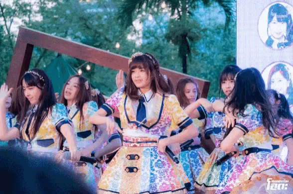 a group of girls are dancing in front of a sign that says ' aea ' on it