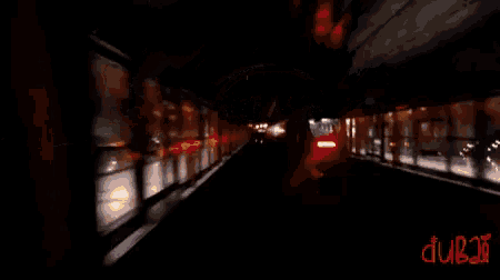 a blurry picture of a train going through a tunnel with dubai written in red