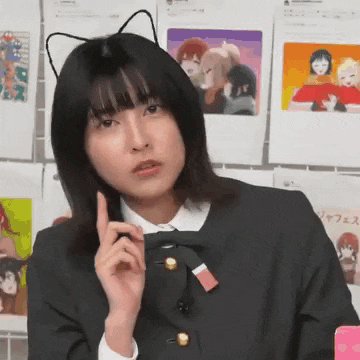 a woman wearing a cat ear headband is making a funny face while pointing up .