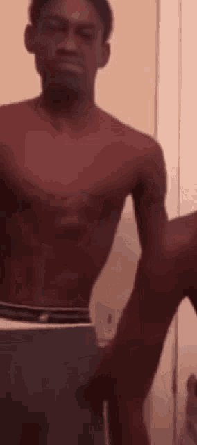 a shirtless man in underwear is standing in front of a mirror in a bathroom .