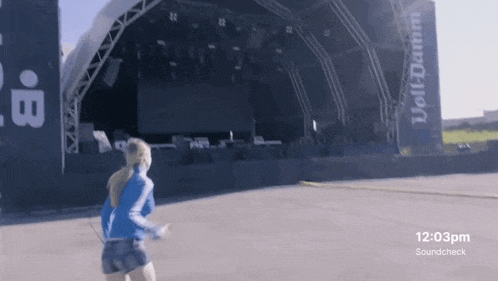 a woman is running in front of a large stage that says volldamm