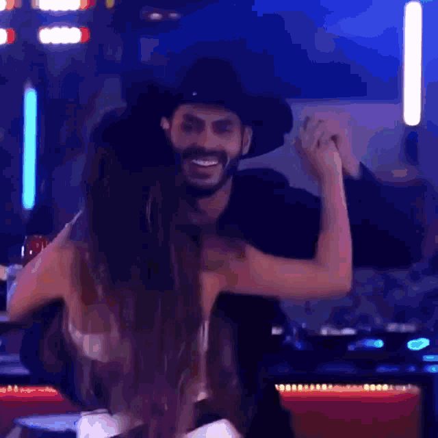 a man in a cowboy hat is dancing with a woman in a white bra .