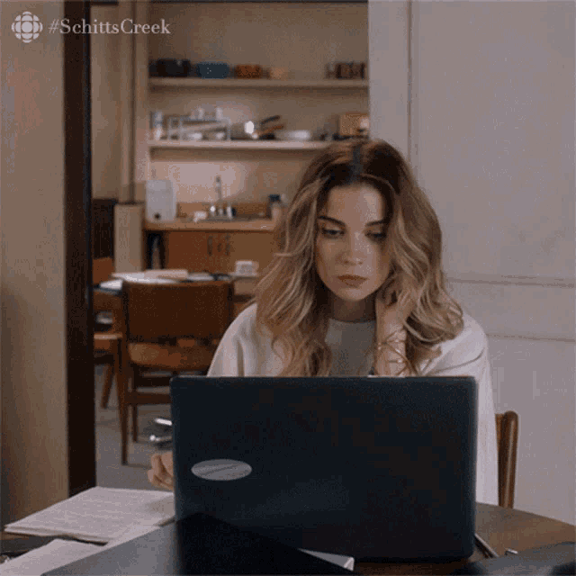 a woman is sitting at a desk using a laptop with the hashtag schitts creek