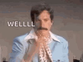 a man with a mustache is wearing a blue suit and tie and is saying well .