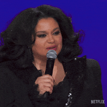 a woman singing into a microphone with uh-kaaay written in white
