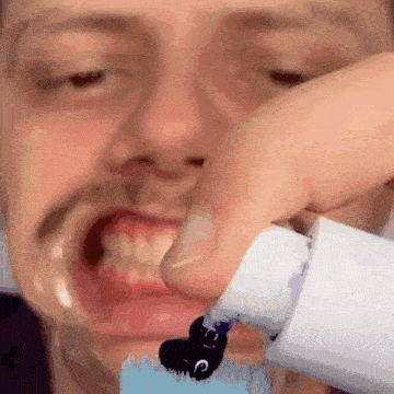 a close up of a man applying toothpaste to his mouth