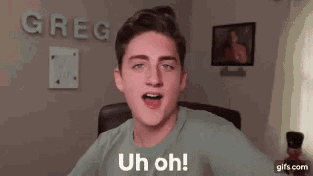 a young man is sitting in a chair in front of a computer and making a funny face while saying uh oh .