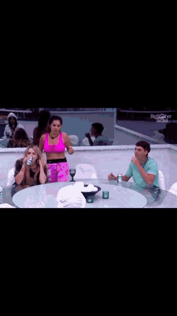 a group of people sitting around a table with a big brother brasil logo on the wall behind them