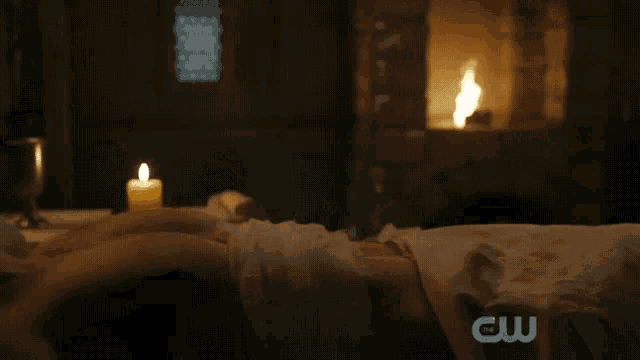 a person laying on a bed with a candle and a cw logo in the corner