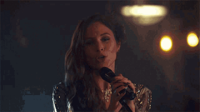 a woman singing into a microphone with the words girls are like guns written above her