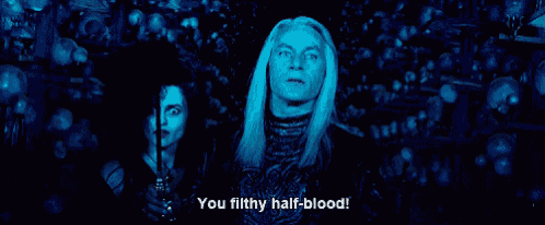 a man and a woman are standing in a dark room and the man is saying you filthy half-blood