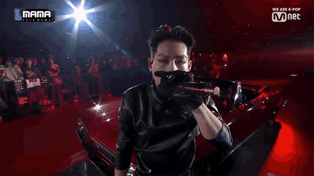 a man in a black leather jacket is standing in front of a red car that says mama on the screen