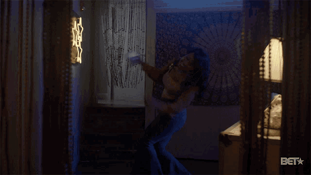 a woman is dancing in a room with a bet logo on the bottom