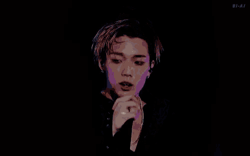 a young man is singing into a microphone while wearing a black shirt .