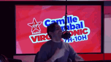 a man is dancing in front of a virgin radio screen