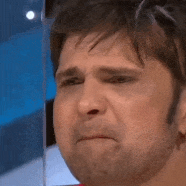 a man with a beard is crying with a tear coming out of his eye .