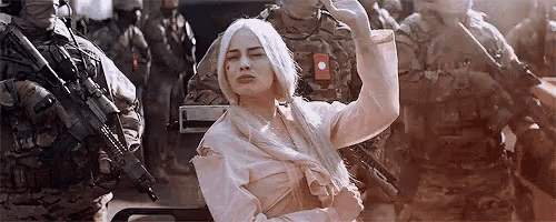 a woman is standing in front of a group of soldiers holding guns .
