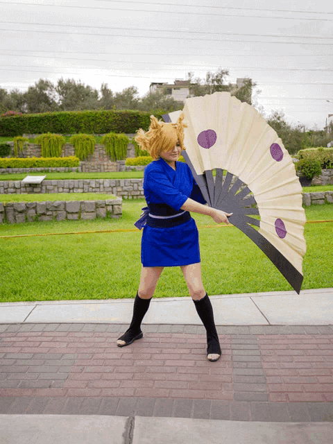 a woman in a blue dress is holding a fan