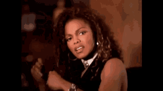 a woman with curly hair is wearing a ring on her finger and a watch on her wrist .