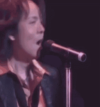 a man in a suit is singing into a microphone on stage .