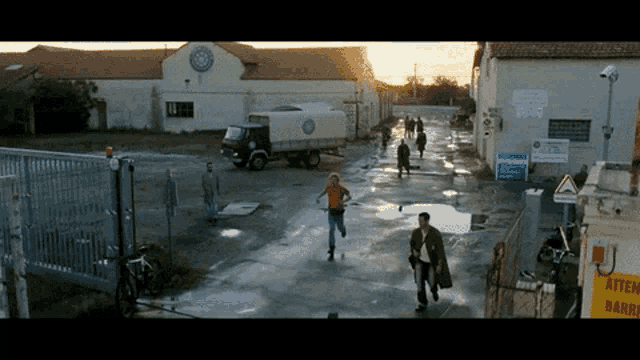 a group of people are running in front of a building that has a sign that says warning