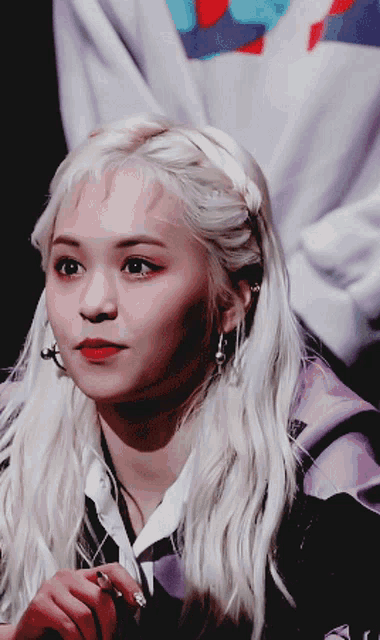 a woman with blonde hair is wearing a purple jacket and earrings