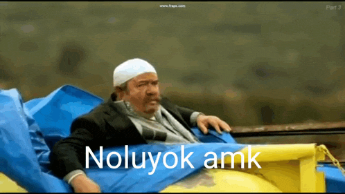 a man with a white hat is laying on a blue and yellow blanket with the words noluyok amk written on it