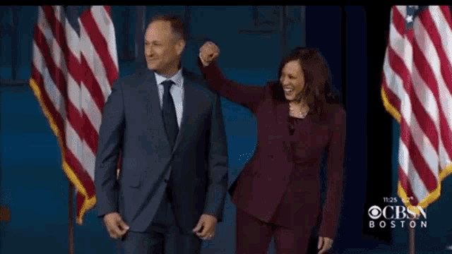 a man in a suit and tie is standing next to a woman in a burgundy suit .