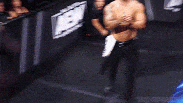 a man without a shirt is standing in front of a sign that says aew