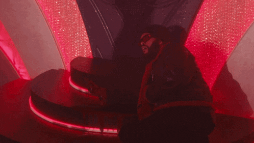 a person is sitting in a dark room with a red light behind them
