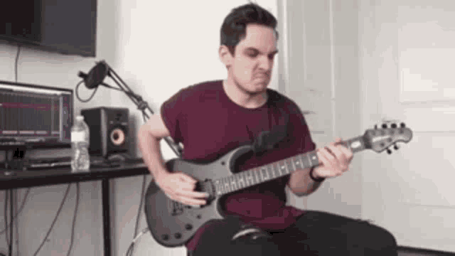 a young man is playing a guitar in a room .