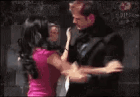 a man in a suit is holding a woman in a pink dress