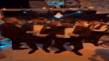 a group of men in tuxedos are dancing together on a dance floor .