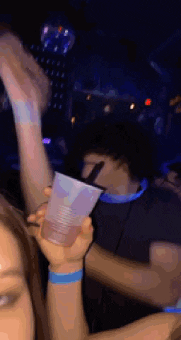 a woman is holding a cup in her hand at a party while a man looks on .