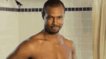 a shirtless man is standing in a shower with a shower curtain .