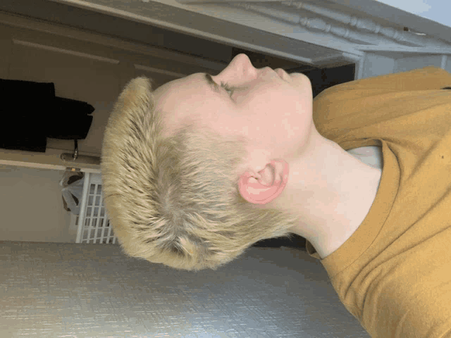 a young man with short blonde hair is laying down