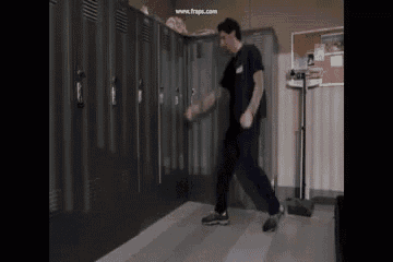 a man in a scrub top is dancing in a room with lockers .