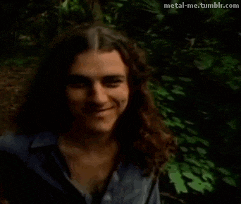 a man with long hair is smiling and looking at the camera .