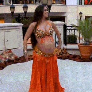 a pregnant belly dancer in an orange outfit is dancing