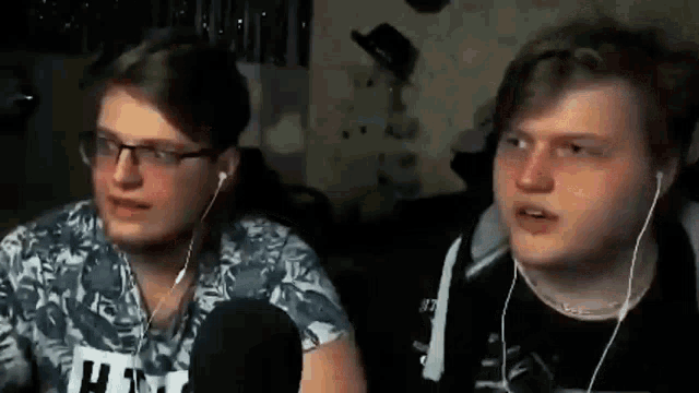 two young men wearing headphones and glasses are sitting next to each other .