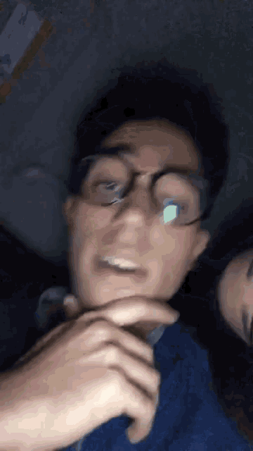 a man wearing glasses and a blue shirt is smiling