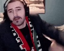 a man wearing headphones and a scarf that says ' chicago ' on it is sitting on a couch
