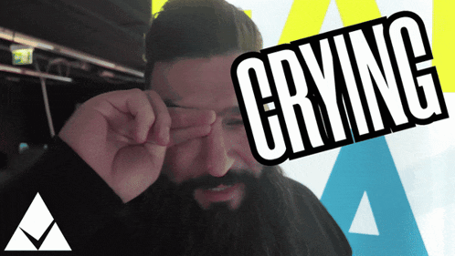 a man with a beard is crying and covering his eyes with his hands